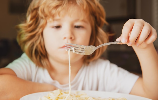 Porträt eines süßen Jungen, der Pasta Spaghetti isst, Nahaufnahme, kaukasische Kinder, Gesicht, Nahaufnahme, Spaß