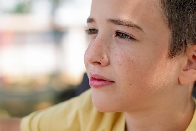 Foto porträt eines süßen jungen im profil, der wegblickt. es gibt freckles auf seinem gesicht.