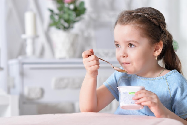 Porträt eines süßen kleinen Mädchens, das köstlichen Joghurt isst