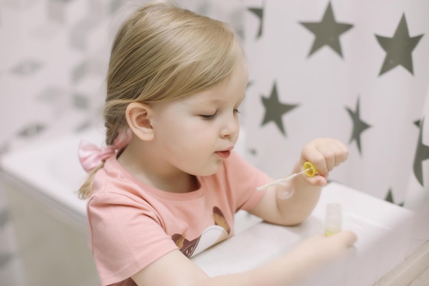 Porträt eines süßen kleinen Mädchens, das zu Hause mit Wasser und Seifenblasen in einem Waschbecken spielt