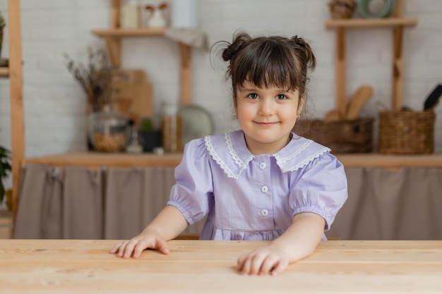 Porträt eines süßen kleinen Mädchens in einem lila Kleid in der Küche. Karte, Platz für Text, Banner