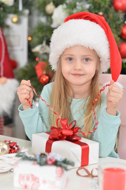 Porträt eines süßen kleinen Mädchens mit Neujahrsgeschenken in Santa's Hut