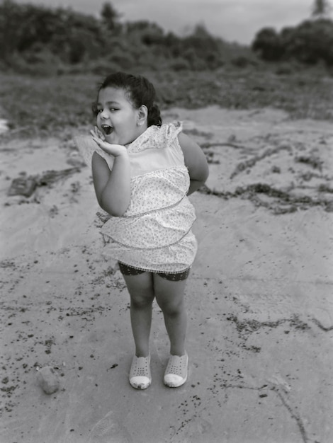 Foto porträt eines süßen mädchens, das am strand steht