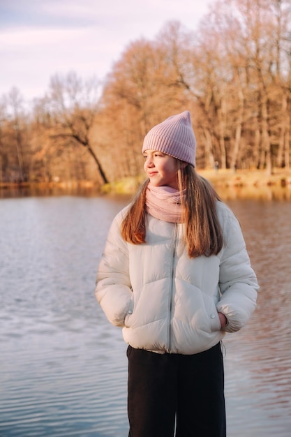 Porträt eines Teenager-Mädchens, das wegschaut und lässige Herbstkleidung in einem Herbstpark mit See im Freien trägt