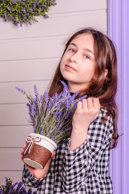 Porträt eines Teenager-Mädchens in einem karierten Kleid Mädchen mit einem Blumentopf in ihren Händen