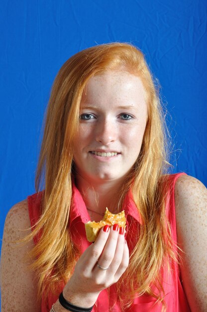 Foto porträt eines teenager-mädchens mit gebackenem essen, das an der wand steht