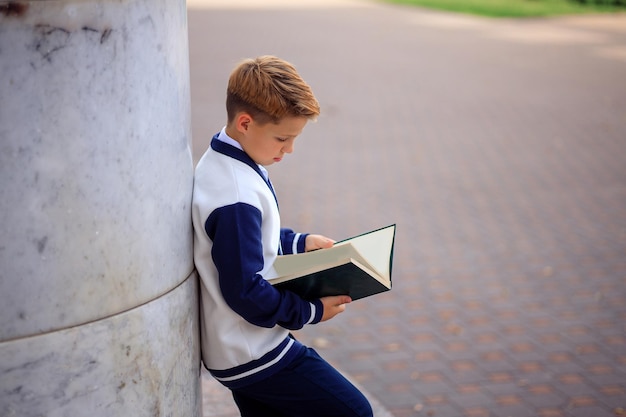 Porträt eines Teenager-Schülers mit einem Buch in seinen Händen in der Nähe des Schulgebäudes