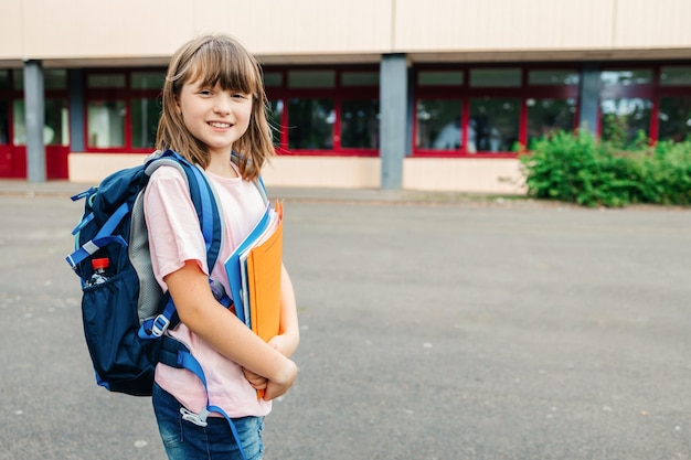 Foto porträt eines teenager schulmädchens vor dem schulgebäude, in dem kinder das schuljahr beginnen