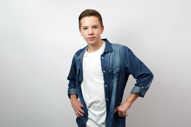 Porträt eines Teenagerjungen in einem Jeanshemd, der mit einem Lächeln in die Kamera schaut, weißer Hintergrund mit Kopierraum