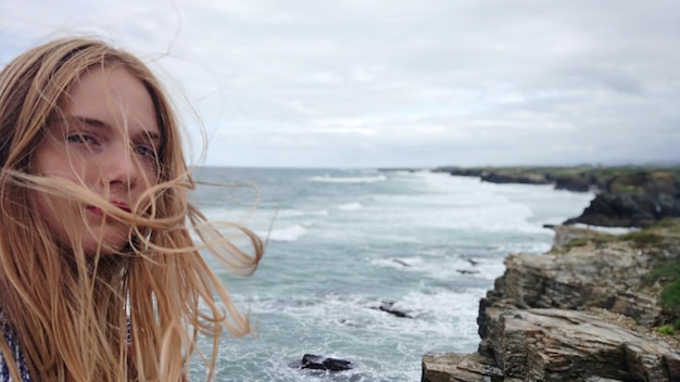 Foto porträt eines teenagermädchens mit zerzaustem haar vor dem meer am strand