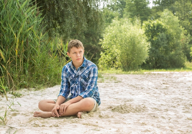 Porträt eines Teenagers, der am Strand sitzt