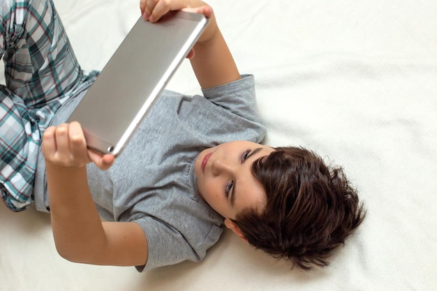 Porträt eines Teenagers liegt auf seinem digitalen Tablet