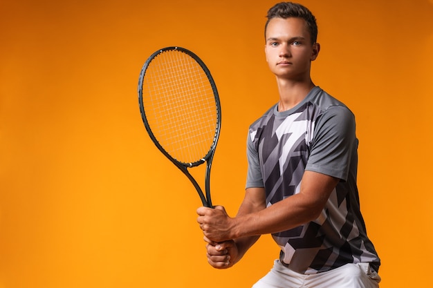 Porträt eines Tennisspielers eines jungen Mannes auf orange Hintergrund nahe