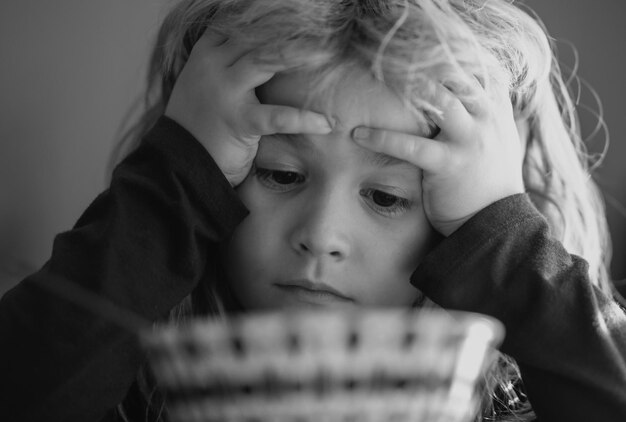 Foto porträt eines traurigen kindes, das zu hause frühstückt porträt eines süßen kleinen jungen mit blonden haaren beim essen