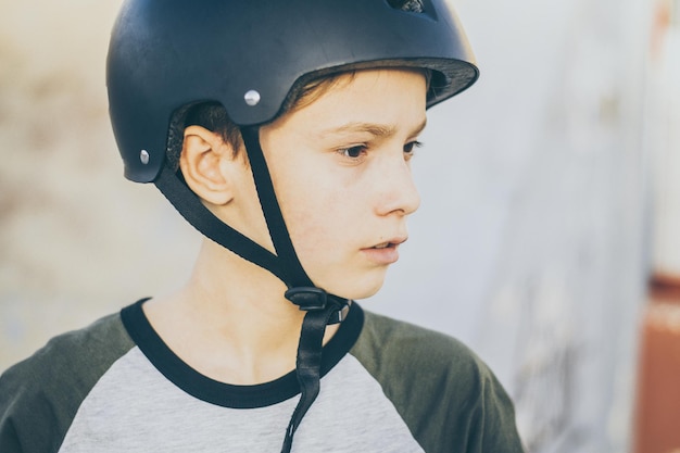 Porträt eines trendigen jungen Skaters im Skatepark mit Helm, der wegblickt, ein Teenager, der sich im Freien erfreut