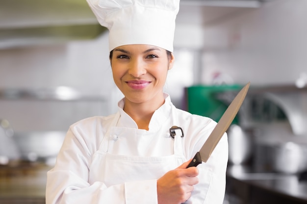 Porträt eines überzeugten weiblichen Kochs, der Messer hält