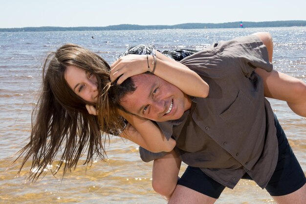 Porträt eines Vaters, der Tochter am Strand huckepack fährt