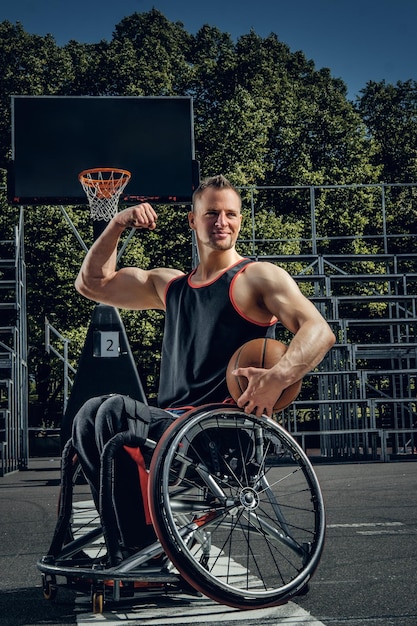 Porträt eines verkrüppelten Basketballspielers im Rollstuhl auf einem offenen Spielfeld.