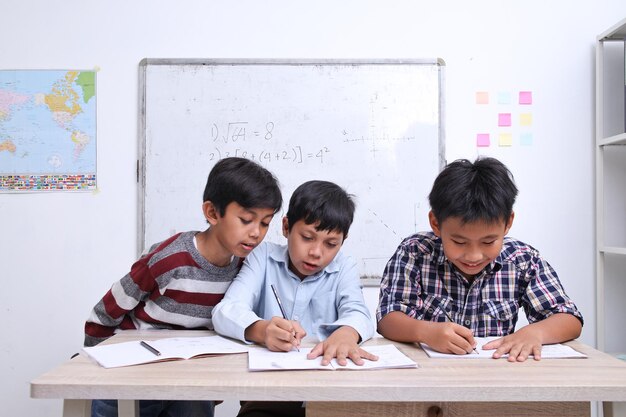 Porträt eines vielseitigen Schülers, der zusammen im Klassenzimmer lernt, Mathematik auf Büchern zu schreiben