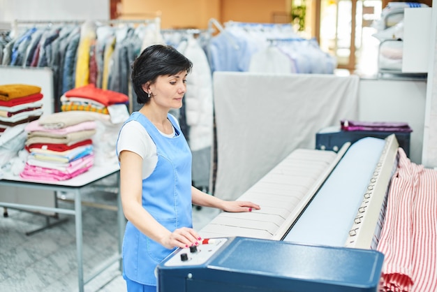 Porträt eines Wäschereiarbeiters auf dem Hintergrund von Kleidern auf Kleiderbügeln in der chemischen Reinigung