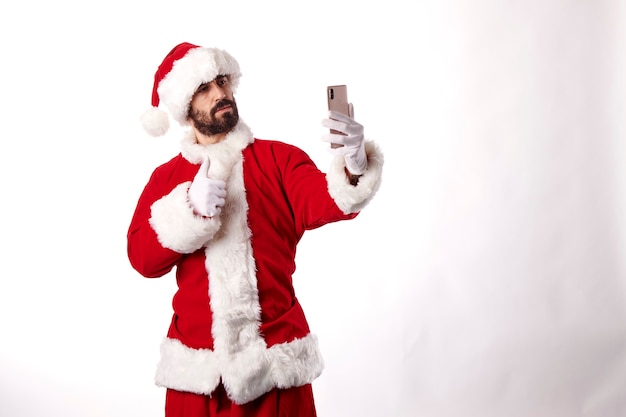 Porträt eines Weihnachtsmannes, der ein Selfie mit einem Smartphone auf weißem Hintergrund macht