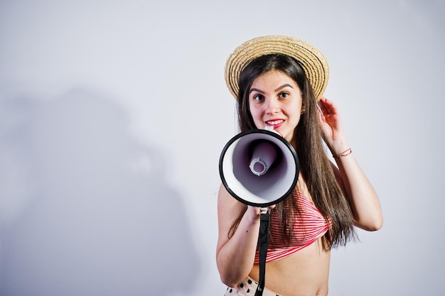 Porträt eines wunderschönen jungen Mädchens in Badeanzug und Hut spricht im Studio in Megaphon