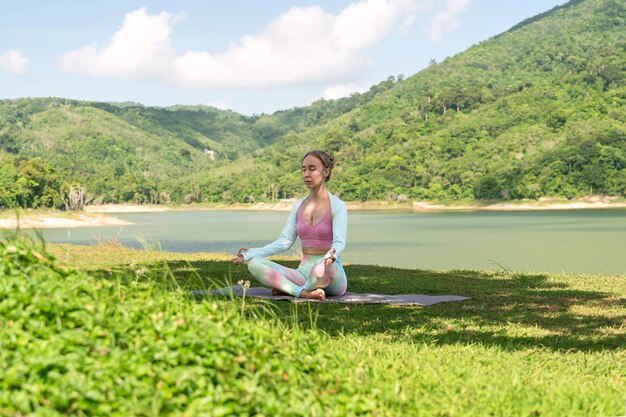 Foto porträt eines yoga-mädchens, das im lotussitz am ufer der bucht sitzt und meditiert. das foto fängt sie in hellem licht ein