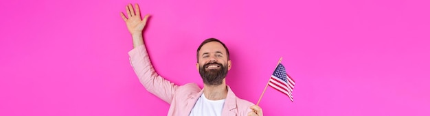 Porträt eines zufriedenen jungen Mannes mit Bart mit amerikanischer Flagge auf rotem Studiohintergrund Großer US-Patriot und Verteidiger der Freiheit