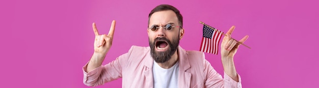 Porträt eines zufriedenen jungen Mannes mit Bart mit amerikanischer Flagge auf rotem Studiohintergrund Großer US-Patriot und Verteidiger der Freiheit