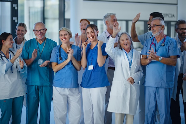Porträt glücklicher Ärzte, Krankenschwestern und anderes medizinisches Personal, das im Krankenhaus applaudiert