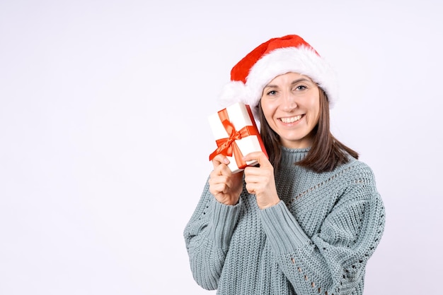 Porträt glücklicher Frau mit Weihnachtsmannhut und Pullover mit Geschenkkiste auf weißem Hintergrund
