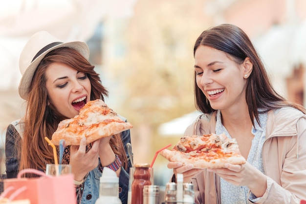 Porträt glücklicher junger Freundinnen, die Pizza essen