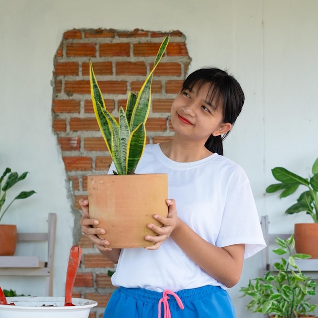 Porträt glückliches junges Mädchen mit Grünpflanzen zu Hause Asiatisches Mädchen