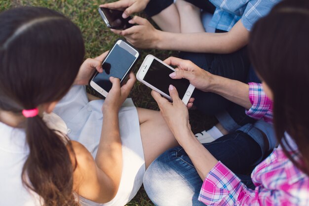 Porträt im Freien von positiven Kindern, die mit Telefonen spielen