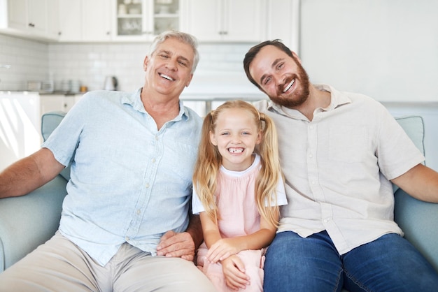 Porträt im Haus Mädchen mit Vater und Großvater auf dem Sofa im Wohnzimmer in Australien Glückliche Familie mit älterem Großelternlächeln zusammen in der Lounge und Mann der älteren Generation entspannen sich auf der Couch mit Kind