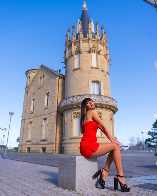 Porträt im roten Kleid im schönen Schloss attraktives lächelndes Sitzen des Mädchens