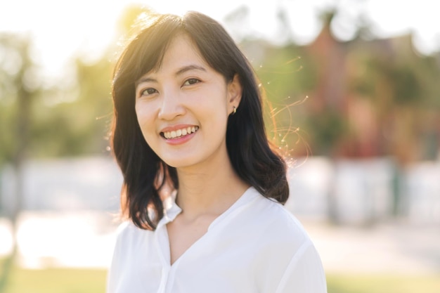 Foto porträt junge schöne asiatische frau mit glücklichem lächeln um park im freien am sonnigen sommertag