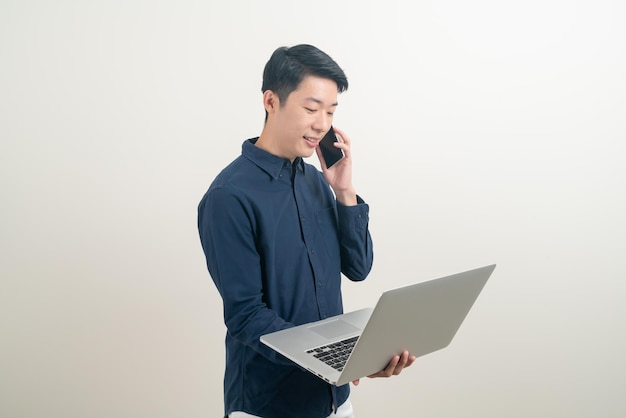 Porträt junger asiatischer Mann sprechen Smartphone oder Handy und Hand mit Laptop auf weißem Hintergrund