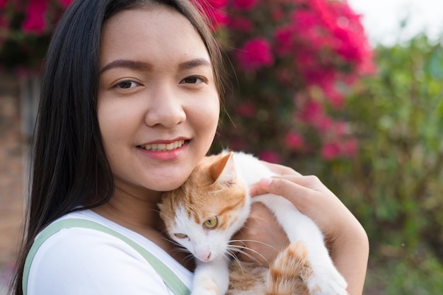 Porträt Junges asiatisches Mädchen mit einem schönen Blumenhintergrund der Katze im Freien