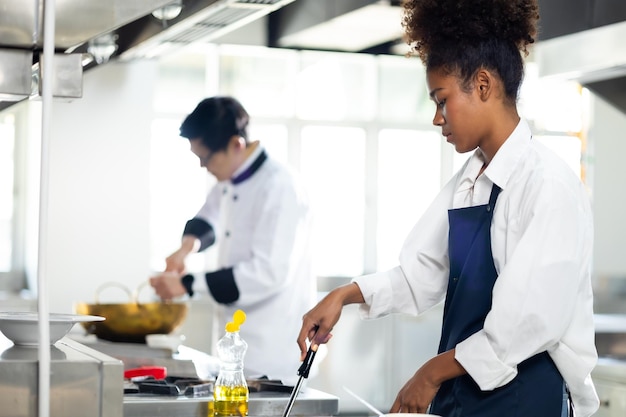 Porträt junges Teenager-Mädchen Koch-Student Kochunterricht kulinarischer Klassenzimmer glückliche junge afrikanische Frau Studenten halten frisches Gemüse zum Kochen in der Kochschule