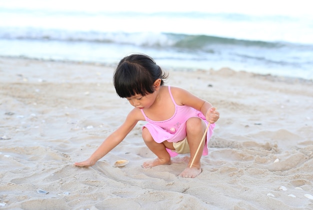 Porträt Kindermädchen, das Sand am Strand spielt