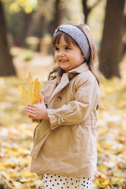 Porträt kleines Mädchen in einem beigen Mantel geht in den Herbstpark