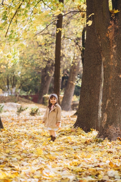 Porträt kleines Mädchen in einem beigen Mantel geht in den Herbstpark