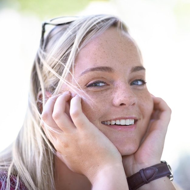 Foto porträt lächeln und schönheit der frau im freien berühren haut und gesichtsausdruck im sommer glückliches gesicht und hände von blonden weiblichen person natürlich und selbstbewusst junges mädchen in der natur in der schweiz