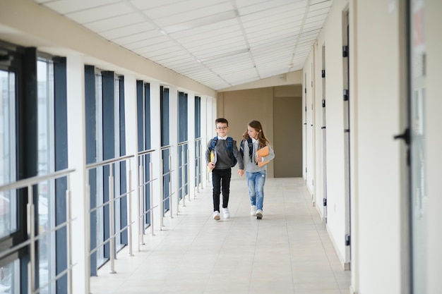 Porträt lächelnder Schulkinder im Schulkorridor mit Büchern