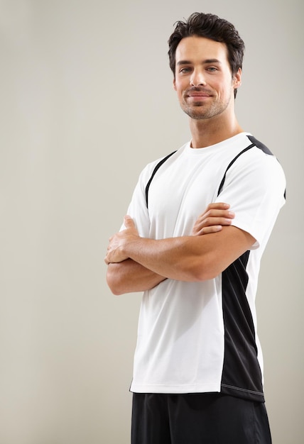 Porträt mit verschränkten Armen oder Athlet im Studio für Fitness-Workout, Sportübungen oder gesundes Wohlbefinden. Mockup mit raumgrauem Hintergrund oder Mann, der bereit ist, mit Selbstvertrauen, Disziplin oder Stolz mit dem Training zu beginnen