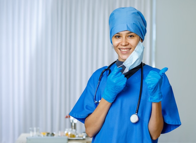 Porträt-Nahaufnahme einer glücklichen, schönen Ärztin in Freiheit trägt einen blauen Krankenhausanzug mit einem lächelnden Stethoskop.