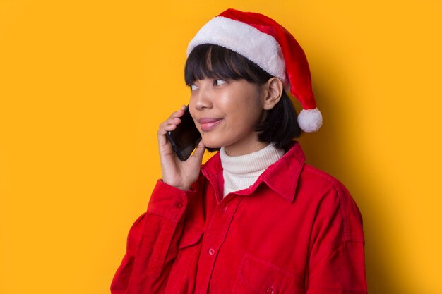 Porträt schöne asiatische Frau tragen Santa Weihnachtsmütze, die am Telefon spricht