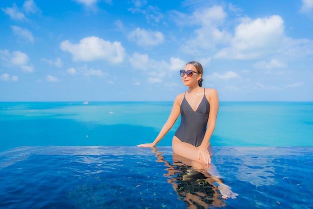 Porträt schöne junge asiatische Frau entspannen Lächeln Freizeit um Freibad im Resort Hotel mit Meerblick