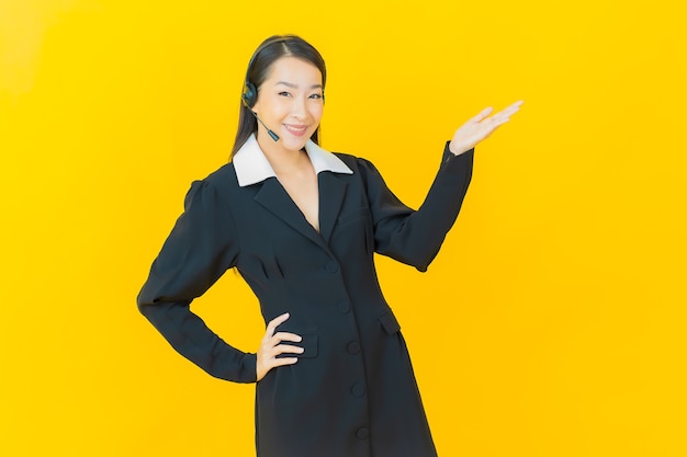 Porträt schöne junge asiatische frau mit Callcenter-Kundenbetreuungszentrum auf gelber Farbwand